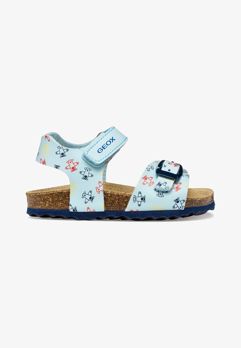 Sandale bleu clair pour enfant avec motifs d'avions, semelle en liège, bride de cheville réglable en velcro étiquetée GEOX, et boucle bleu marine sur la bride avant.