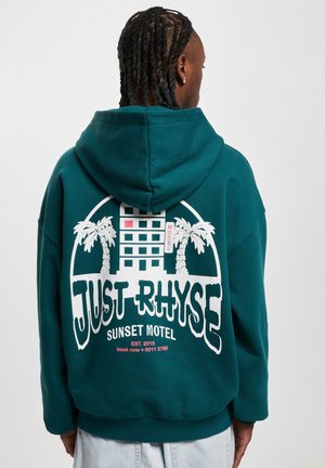 Teal hooded sweatshirt featuring a large white graphic on the back with "JUST RHYSE" and "SUNSET MOTEL," palm trees, and a building design.