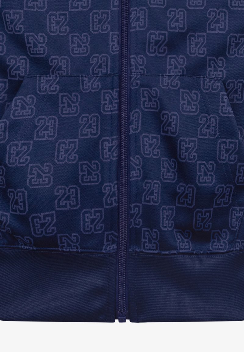 Veste bleu marine avec un motif répété des chiffres 23, fermeture éclair à l'avant, tissu doux au toucher et ourlet et poignets côtelés.
