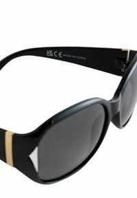 Occhiali da sole neri con lenti sfumate, oversize, realizzati in plastica lucida. Presentano un dettaglio dorato sulle astine. L'etichetta riporta "UK CA CE Made in China."