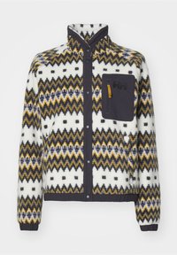Veste en polaire avec col montant, fermeture devant par boutons-pression, poche poitrine noire avec fermeture éclair et motif zigzag en blanc, jaune, gris et noir.