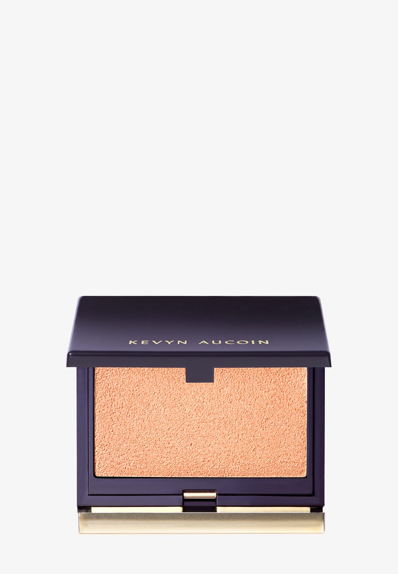 Boîtier en poudre Kevyn Aucoin avec un écrin bleu marine et des accents dorés, contenant une poudre texturée de couleur pêche.