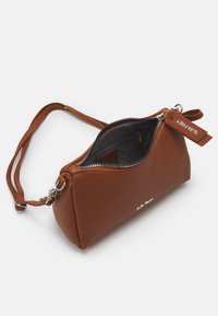 Hnědá kožená crossbody taška s texturou, s mírně otevřeným stříbrným zipem, nastavitelným popruhem a značkovou visačkou připevněnou poblíž táhla zipu.