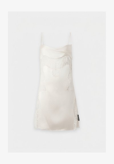 Robe nuisette en satin blanc avec des détails en dentelle et fines bretelles, suspendue sur un fond blanc.