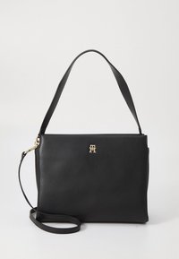 Sac à main en cuir noir au design structuré, avec un logo doré et une bandoulière réglable. Texture lisse, forme rectangulaire, avec une poignée supérieure.