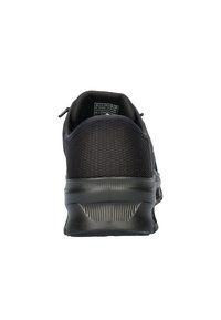 Chaussure de sport noire avec une tige en maille texturée, un talon arrondi, une semelle en caoutchouc et une languette au talon pour un enfilage facile.
