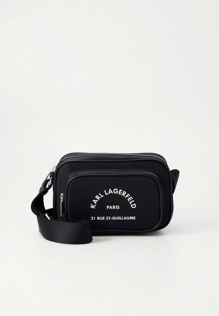 Sac bandoulière en nylon noir avec bandoulière réglable, portant un texte de marque blanc, de forme rectangulaire, et doté de deux compartiments zippés.