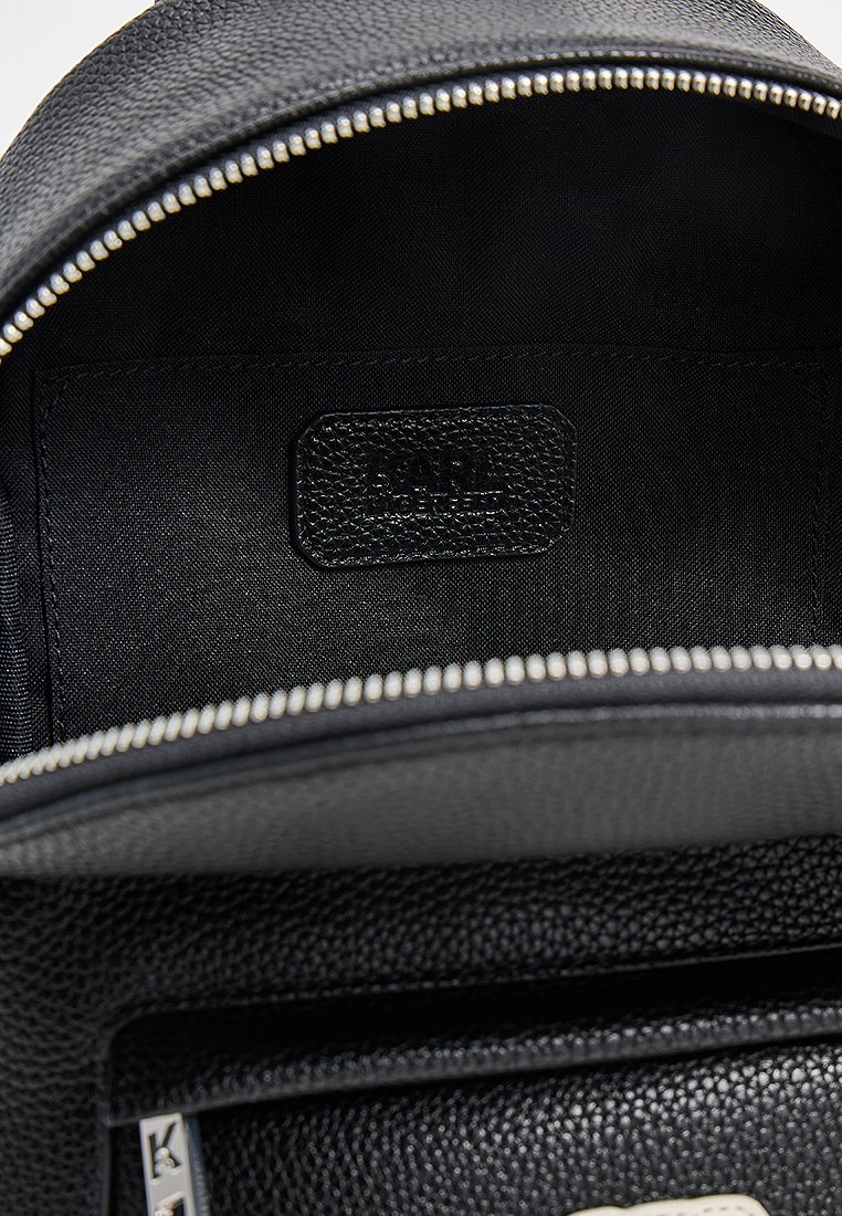 Wnętrze czarnego skórzanego plecaka o gładkiej fakturze, z zamknięciem na zamek, minimalistycznym designem i metką marki w rogu.