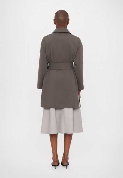 Grau belted Mantel mit breitem Kragen, im A-Linien-Silhouette. Getragen über einem hellgrauen, plissierten Rock. Glatte Textur.