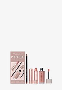 Zestaw Pucker Up Lip Trio składa się z różowego pudełka z trzema elementami: kredką do ust, pomadką i płynnym kolorem do ust w dopasowanych odcieniach nude.