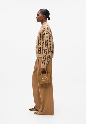 Tan knitted sweater with a cable pattern, oversized tan trousers, and a small brown handbag featuring white text; leopard print shoes.