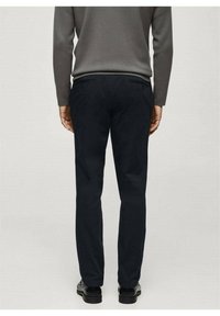 Marineblaue Hose aus glattem Stoff mit gerade geschnittenem Design, Gesäßtaschen und kombiniert mit schwarzen Schuhen.