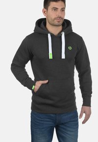 Grijze hoodie met een voorzak, witte trekkoorden en een groen accentlogo. Gemaakt van zachte materialen, met een standaard pasvorm en geribbelde manchetten.