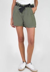 Shorts vert olive avec une ceinture en tissu noir, présentant des plis, des poches latérales et une coupe ajustée. Matière en mélange de coton avec une texture lisse.