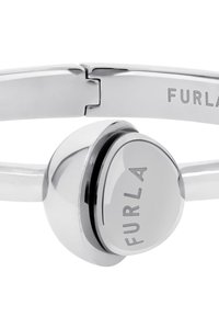 Hõbedatooni käevõru, millel on ümar keskne element, millel on graveeritud "FURLA" logo, stiilne disain ja sile metallviimistlus.