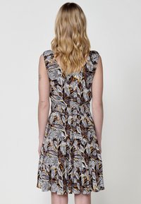 Blumenmusterkleid mit kurzen, ausgestellten Ärmeln, elastischem Bund und gestuftem Rock. Predominant schwarz, orange und gelb auf weißem Hintergrund.