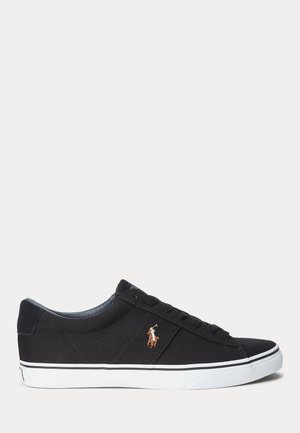 Zwarte lage sneaker met witte zool en een dunne zwarte streep, met een klein geborduurd logo van een polospeler aan de zijkant.