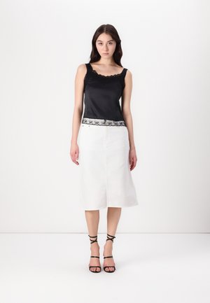 Mustmust tank top, mille pitsiga kaelus ja äär, on kombineeritud valgest denim seelikust. Mustad rihmadega sandaalid täiendavad välimust.