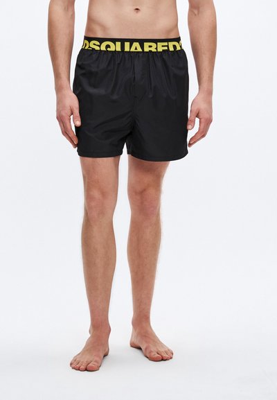 Schwarze Badeshorts mit gelbem elastischem Bund mit "DSQUARED2"-Logo, versehen mit einer leichten, glatten Textur und einem einfachen, maßgeschneiderten Schnitt.