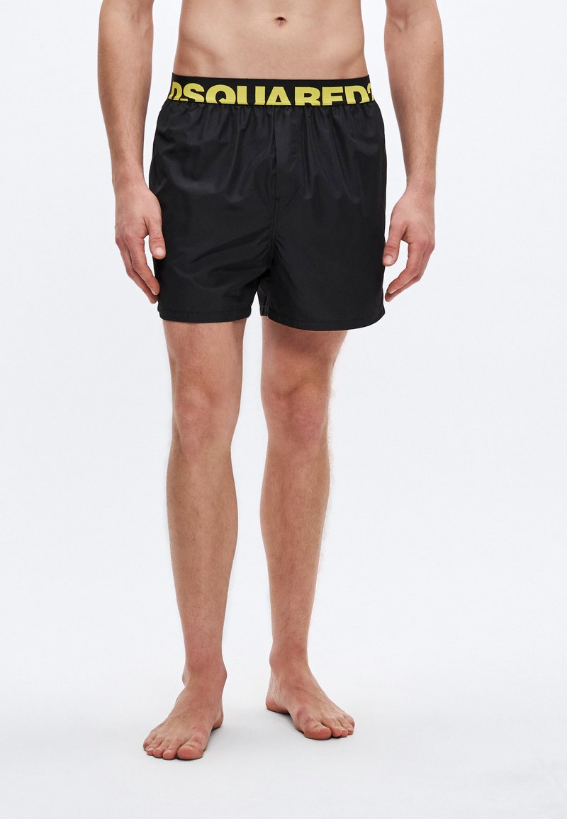 Fekete fürdőnadrág sárga "DSQUARED2" márkájú gumis derékpánttal, könnyű, sima textúrával és egyszerű, szabott szabással.