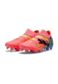 Scarpini da calcio di un vivace colore rosa con una parte superiore testurizzata, dotati di accenti gialli e di un design geometrico colorato sul lato, completati da una suola blu.