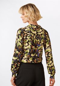 Blusa a maniche lunghe nera con un motivo colorato a vortice in verde, giallo, blu e arancione, dotata di colletto rotondo e spalle arricciate.
