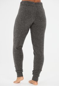 Gray, fitted sweatpants made of soft, textured fabric with a tapered leg and ribbed cuffs. Features a stretchy waistband for comfort.
