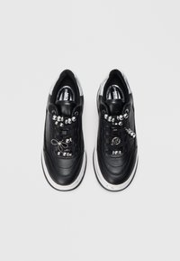 Musthave nahkased spordijalatsid hõbedaste aktsentidega, kaunistusena kett ja helmed paelte ääres ning valge kummist tald. Sujuv tekstuur.