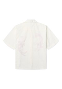 Chemise blanche à manches courtes avec une coupe décontractée, col ouvert et motifs floraux discrets dans le dos.