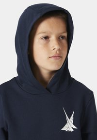 Sudadera con capucha azul marino de textura suave; presenta un diseño de logo blanco en el pecho. La capucha está forrada, lo que mejora la calidez y el estilo.