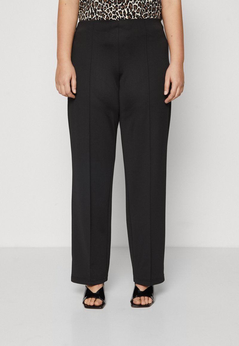 Zwarte op maat gemaakte broek met een gladde textuur, voorzien van voorplooien en een rechte pijp, gecombineerd met zwarte sandalen met open tenen.