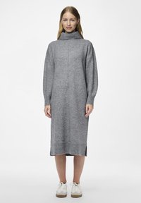 Γκρί πλεκτό φόρεμα με ψηλό λαιμόκοψη, ριμπ μανσέτες και στρίφωμα, πλευρικές σχισμές και χαλαρή εφαρμογή. Συνδυασμένο με λευκά αθλητικά παπούτσια.