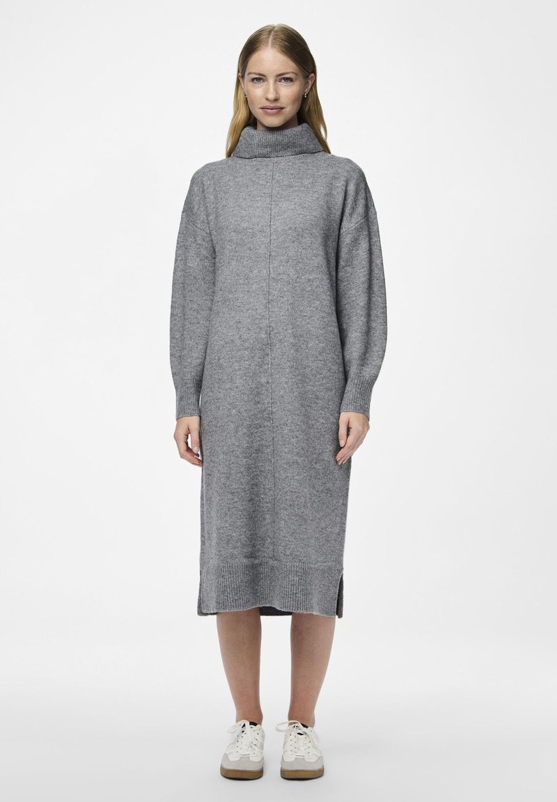 Γκρί πλεκτό φόρεμα με ψηλό λαιμόκοψη, ριμπ μανσέτες και στρίφωμα, πλευρικές σχισμές και χαλαρή �εφαρμογή. Συνδυασμένο με λευκά αθλητικά παπούτσια.