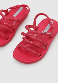 Sandalias de plástico rojo con múltiples correas superpuestas, plantilla texturizada y logo. Apertura amplia para los dedos y diseño de suela plana.