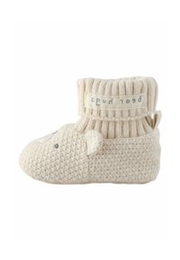 Pantofole in stile calza lavorate a maglia in beige con un motivo a faccia di orso, corpo testurizzato, risvolto a coste e un'etichetta in tessuto. Design morbido e flessibile.