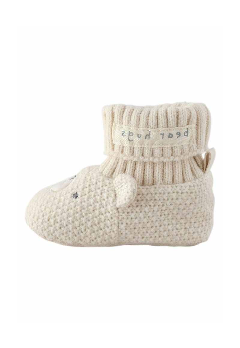 Pantofole in stile calza lavorate a maglia in beige con un motivo a faccia di orso, corpo testurizzato, risvolto a coste e un'etichetta in tessuto. Design morbido e flessibile.