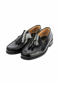 Mocasines de cuero negro con textura suave, diseño de punta redonda, borlas decorativas y tacón bajo. Interior forrado con material beige.