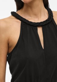 Fekete, pánt nélküli felső, amely fonott dekoltázzsal, finom textúrával és elől kulcslyuk részlettel rendelkezik. Az anyag könnyednek és puhának tűnik.