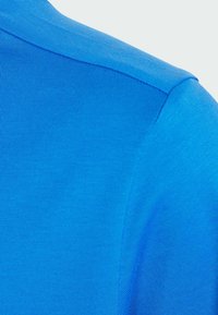 Camicia blu a maniche corte con texture a coste e finitura liscia. Dettaglio di un colore vivace sulla spalla e nell'area delle maniche.