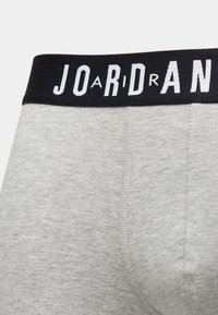 Hallid boxer-püksid musta elastse vöökohaga, millel on valged "JORDAN" tähed. Kangas tundub pehme ja sileda tekstuuriga.