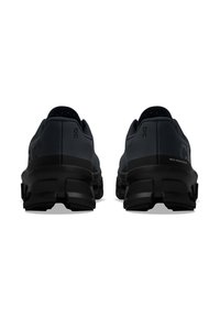 Schwarze Sportschuhe mit einer strukturierten Oberseite, gepolstertem Absatz und einem markanten Sohlen-Design, das segmentierte, erhöhte Bereiche aufweist.