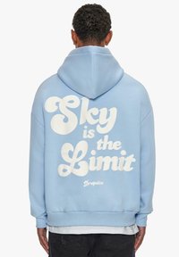 Light blue hoodie featuring a large white printed text "Sky is the Limit" on the back. It has a drawstring hood and ribbed cuffs.