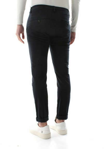 Mørkeblå bukser med slim fit, med to baglommer og opsmøg, parret med hvide sneakers. Glat tekstur og minimalistisk design.
