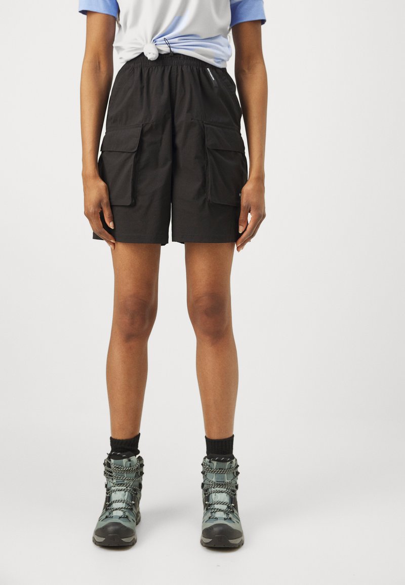 Svart cargo shorts med elastisk midje, med frontlommer og løs passform. Kombinert med kamuflasje snørestøvler.