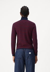 Maglietta a maniche lunghe a righe blu navy e rosse con colletto a coste, caratterizzata da una silhouette aderente e un tessuto a maglia strutturato.