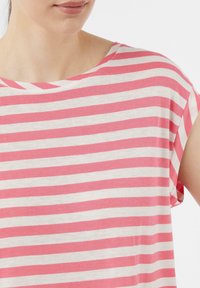Różowa i biała, w paski, koszulka wykonana z lekkiej bawełny, z dekoltem w łódkę i krótkimi rękawami. Miękka tekstura, luźny krój.
