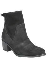 Bottine en daim noir avec un léger talon, présentant une texture lisse, un design minimaliste et une coupe distincte sur les côtés.