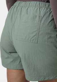 Pantalones cortos ligeros verdes con un acabado texturizado, que cuentan con una cintura elástica y un bolsillo trasero. Diseño informal adecuado para climas cálidos.