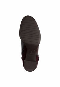 Des chaussures avec une tige bordeaux, présentant des finitions lisses et texturées, une semelle en caoutchouc foncé et un motif de rainures horizontales pour une meilleure adhérence.