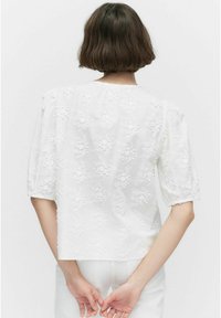 Witte geborduurde blouse met korte pofmouwen, met bloemmotieven, een gestructureerde afwerking en een rechte zoom aan de achterkant.